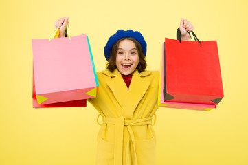 Shop with discount card. Get discount shopping on birthday or holiday. Fashionista adore shopping. Obsessed with shopping. Girl cute kid hold shopping bags on yellow background. Mid season sale