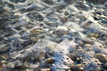 pebble stones on the sea beach, the rolling waves of the sea with foam