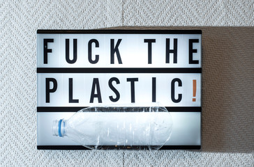Message Fuck the plastic! on illuminated board. Ecology concept with text.