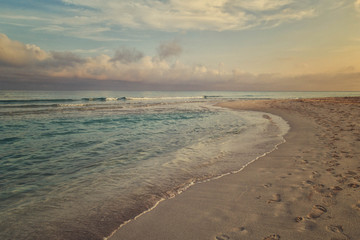 Fototapeta na wymiar Morning surf, clouds and footprints at the beach of Varadero, Cuba