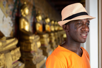 Young happy African tourist man smiling at Buddhist temple