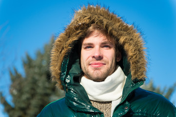 Man unshaven wear warm jacket with fur snowy nature background. Guy wear winter jacket with furry...