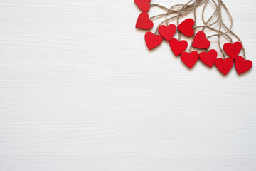 Valentines Day background. Red wooden hearts on white wooden background. Copy space, top view.