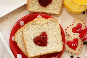 Valentines day breakfast in bed  sandwich with red jam hearts coffee on a white tray