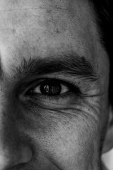 Fragment of a man's face: left eye and nose to compile an identikit. Fragment of the wrinkled face of a young guy. Smiling eyes of a man. Black and white photo.