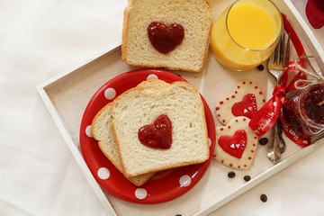 Valentines day breakfast in bed  sandwich with red jam hearts coffee on a white tray