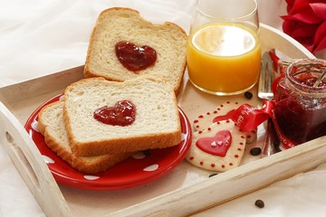 Valentines day breakfast in bed  sandwich with red jam hearts coffee on a white tray