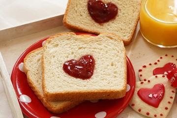 Valentines day breakfast in bed  sandwich with red jam hearts coffee on a white tray