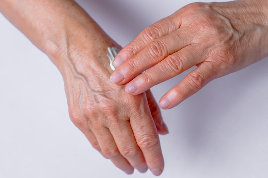  Skin care. Elderly woman applies Cream On Her Hands.  Beauty produc.