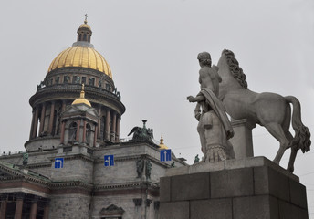 Obraz premium St. Isaac's Cathedral, in the foreground a sculpture of the young man taming a horse, a sculpture is before an entrance the Konnogvardeyskiy manage.St-Petersburg, Russia.