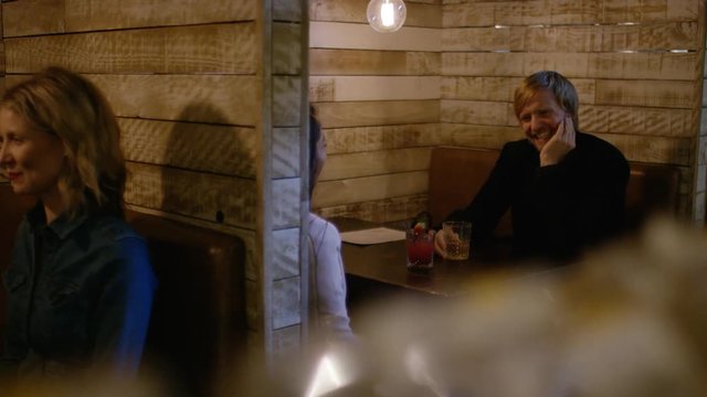 People in booths in a bar talking with each other