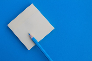 Top view of the empty blank  for writing and blue pencil on the blue background.Copy space.