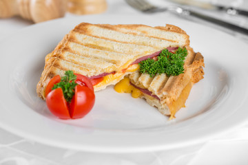 Sandwich with ham and cheese on a white plate.