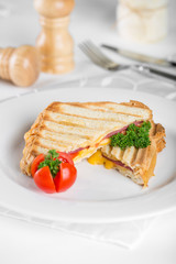 Sandwich with ham and cheese on a white plate.