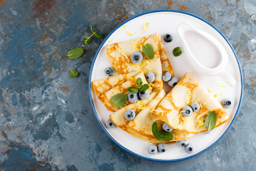 Sweet pancakes wrapped with fresh berries, crepes with blueberry, top view.