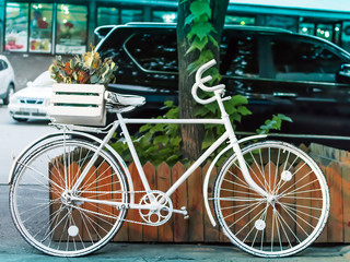 Painted white bike on the street of a European city near the road with cars