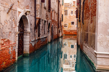 Grand canal between ancient houses in Italy, reflecting blue water building, warm summer day