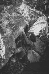 man climbs hard boulder outdoor, black and white