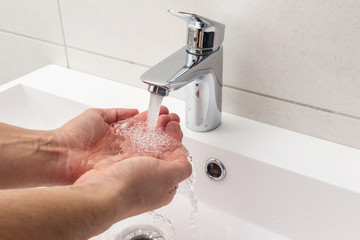 Washing hands under the faucet with running water, hygiene concept