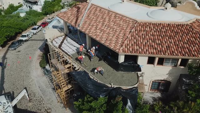Aerial shot of workers pouring concrete in a luxury house with a casting machine.