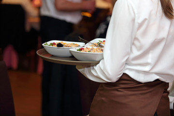 Kelnerka roznosi talerze z jedzeniem na sali w restauracji. - obrazy, fototapety, plakaty