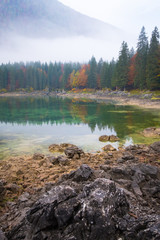 Lake Laghi di Fusine on foggy morning with mountain Mangart