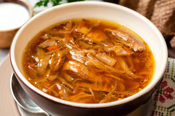 Traditional Russian sauerkraut soup Shchi in bowl on rustic wooden background. Selective focus.