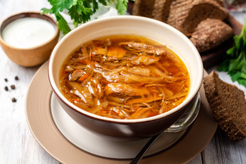 Traditional Russian sauerkraut soup Shchi in bowl on rustic wooden background. Selective focus.