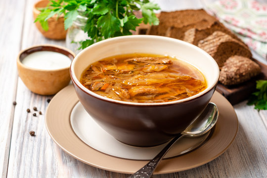 Traditional Russian sauerkraut soup Shchi in bowl on rustic wooden background. Selective focus.