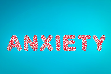 inscription anxiety white and red pills on a blue background top view. concept of antidepressant drugs reduce anxiety