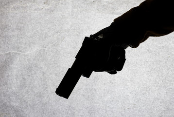 The gun in the hand of men who is ready to shoot at his victim. Breaking the law and crime. Attack...