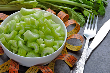 Sliced celery in a bowl and measuring tape. Concept of weight loss with celery.