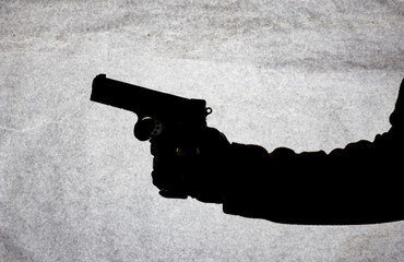 The gun in the hand of men who is ready to shoot at his victim. Breaking the law and crime. Attack...