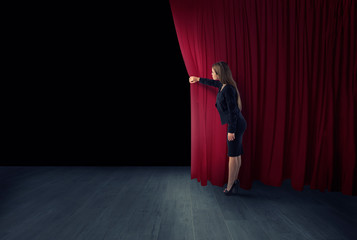Woman open red curtains of the theater stage