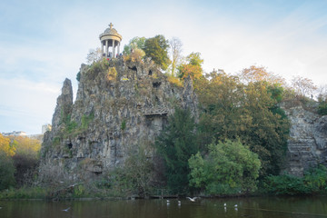 Paris, France - 11 03 2018: Neighborhood of Villette. The park Buttes-Chaumont. Temple of Sybille and the impressive cliff and trees reflecting on the water