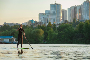 Guy in wetsuit rowing on city river