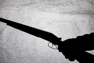 Classic double-barrell smooth-bore hunting rifle on man hand isolated on light stone background