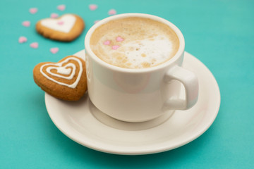 Cup of coffee or latte and heart shaped cookies, biscuits. Blue background, copy space. Caffeine drink lovers. Morning coffee with milk.