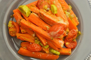 Fried, cooked carrots with green herbs, close up. Vegetarian food.
