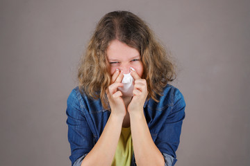 Cold girl blowing her nose in a white napkin.