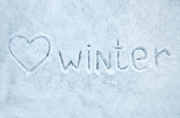 Top view of the English inscription on ice with fresh snow: "I love winter"