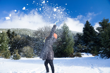Woman throwing snow balls in the air, on a snowy mountainous landscape