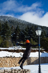Woman is swinging on a lamp post during winter time, on a snowy environment