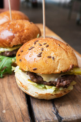 delicious cheeseburgers served on a wooden board