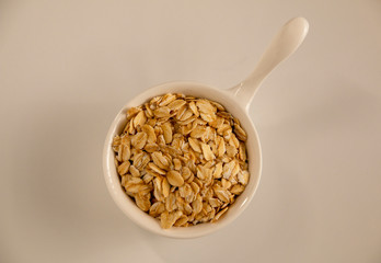 Dry oatmeal in a bowl isolated on white background. View from above.