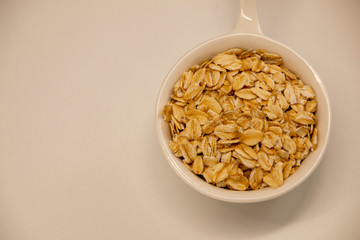 Dry oatmeal in a bowl isolated on white background. View from above.