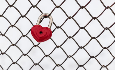 background. a red lock in the shape of a heart is hanging on the fence. Valentine's day holiday.
