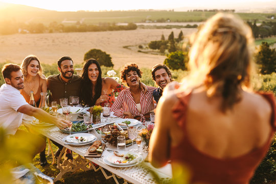 Woman taking picture of friends having dinner party