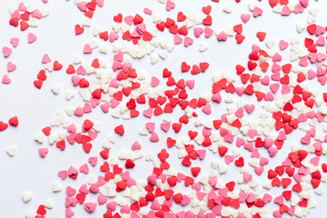 Red, pink and white heart shaped sweets scattered on white background. space for text. flat lay.