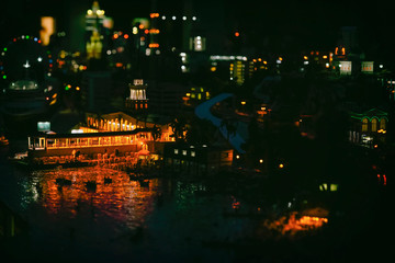 Defocused abstract city with pier, realistic miniature. Bright night urban bokeh, abstract blurred background